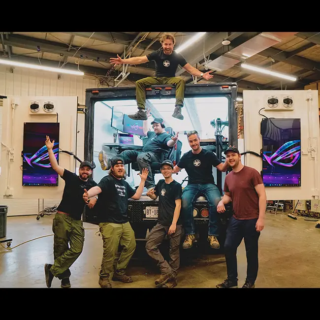 Hacksmith Industries team members cheering in front of the back of a truck