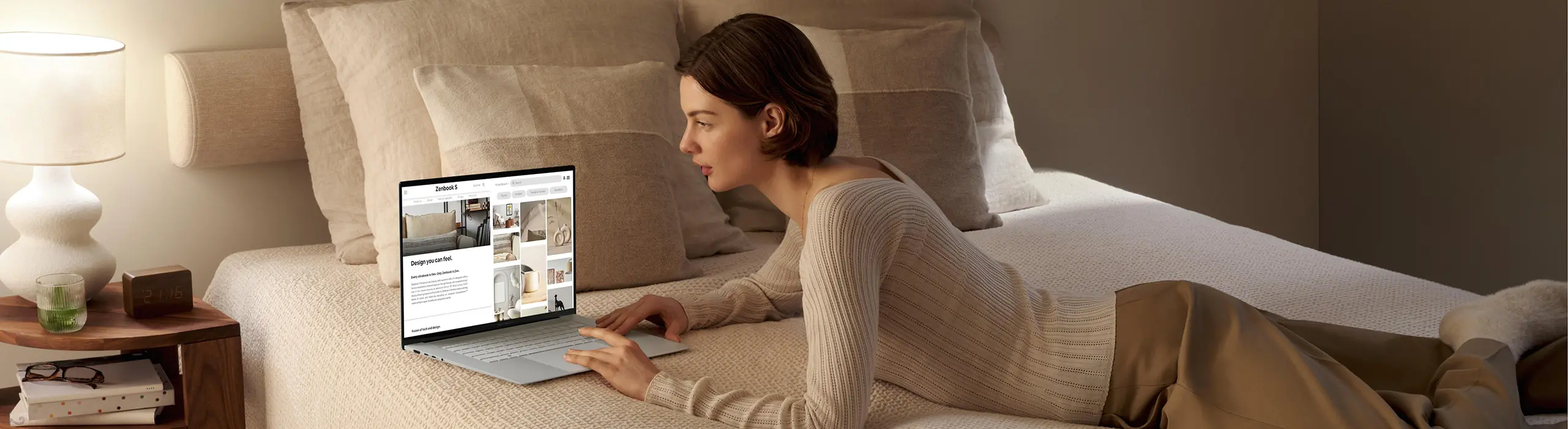 The image shows a woman gracefully using a Zenbook S 16 while lying on the bed.