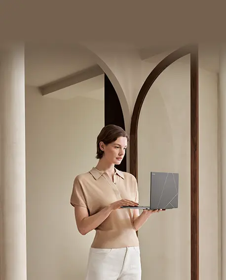 A woman carries a gray Zenbook S 14 with the device open in 90 degree.