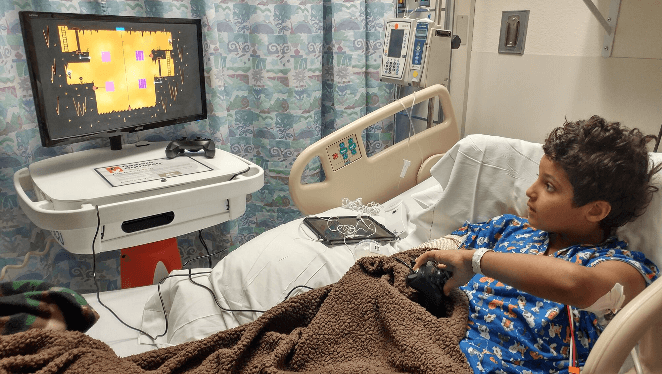 A boy on hospital bed playing games. Gamers Outreach Supports Healing Through Gaming