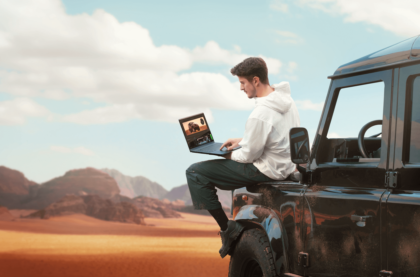 A man sitting on a truck using an ASUS laptop