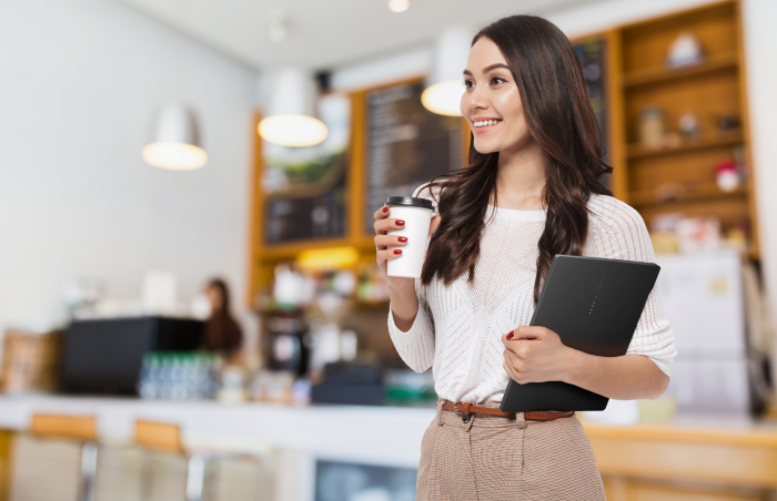 A Woman carrying a laptop and a coffee