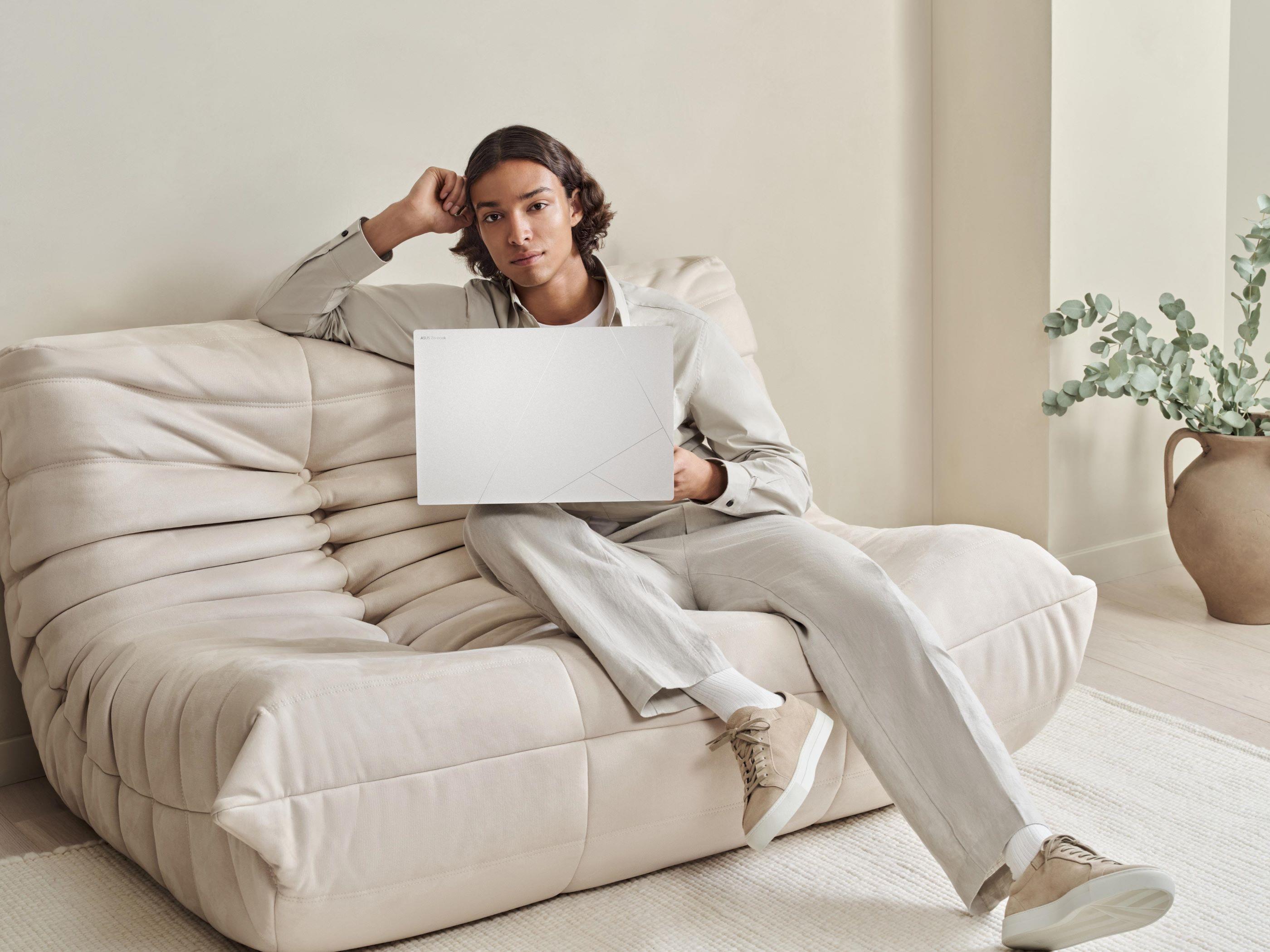 A person in a beige room with an ASUS laptop